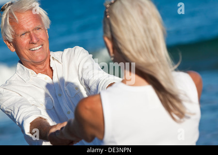Glückliche senior Mann und Frau paar tanzen und Hand in Hand auf einem einsamen tropischen Strand, blaues Meer Stockfoto
