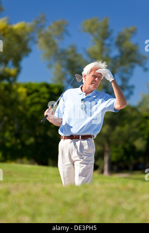 Happy senior woman Golf spielen, in einem Bunker stehen und auf der Suche nach seinen ball Stockfoto