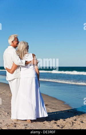 Ältere Mann und Frau Brautpaar zusammen Blick auf das Meer auf einem einsamen tropischen Strand mit strahlend blauem Himmel Stockfoto