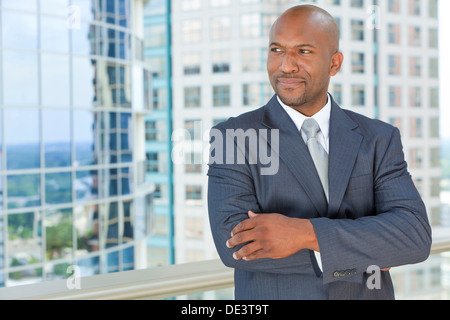 Erfolgreiche afrikanische amerikanische Geschäftsmann oder Mann Arme verschränkt in einem Anzug in einer modernen Stadt Stockfoto