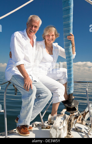 Ein glückliches senior paar sitzen am Bug eines Segelbootes auf einem ruhigen blauen Meer Stockfoto