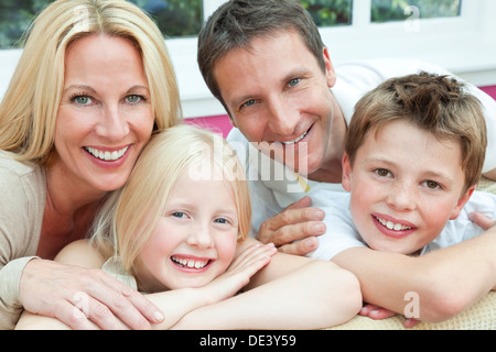 Eine attraktive, Familienglück von Mutter, Vater, Sohn und Tochter sitzen auf einem Sofa zu Hause Spaß Stockfoto