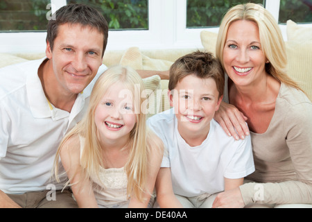 Eine attraktive glückliche Familie von Mutter, Vater, Sohn und Tochter sitzen auf einem Sofa zu Hause Spaß Stockfoto