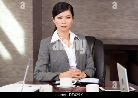Schöne chinesische Asiatin oder Geschäftsfrau sitzen an einem Konferenztisch Stockfoto