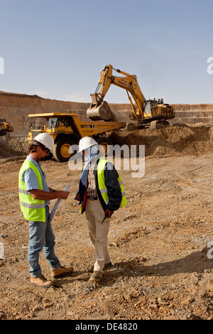 Vorgesetzten anweist Trainee im Tagebau Oberfläche Goldmine Grube mit Bagger und Haul Truck hinter, Mauretanien, NW-Afrika Stockfoto