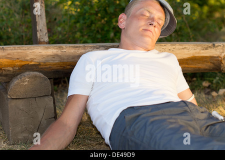 Mann mittleren Alters sitzen im Park auf einer Bank eine angenehme Gefühl nach einer Dosis Heroin gelehnt Stockfoto