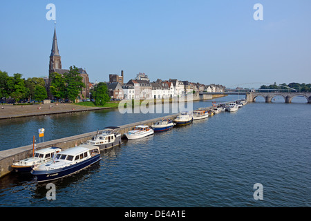 Maastrichter Stadtbild mit Fluss Maas geteilter Wasserstraße und verankertem Motor startet Kirchturm Wahrzeichen blauer Himmel sonnig Limburg Niederlande Europa EU Stockfoto