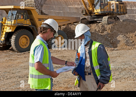 Vorgesetzten anweist Trainee im Tagebau Oberfläche Goldmine Grube mit Bagger und Haul Truck hinter, Mauretanien, NW-Afrika Stockfoto