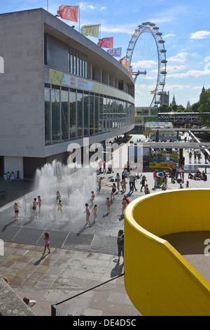 Im Sommer spielen Kinder im Southbank Complex in den erscheinenden Räumen, dem Wasserbrunnen vor der Royal Festival Hall mit London Eye außerhalb von England Großbritannien Stockfoto