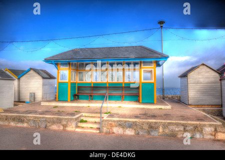 Traditionelles englisches beach Shelter mit Holzbank neben Strandhütten unter blauem Himmel Stockfoto