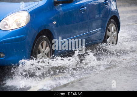 Blaues Auto fahren durch überfluteten Straße. Stockfoto