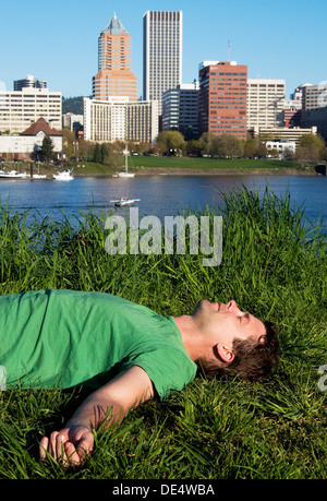 Ein Mann im Gras am östlichen Ufer des Willamette River in Portland, Oregon. Stockfoto