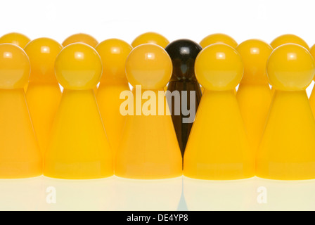 Eine schwarze Figur, umgeben von gelben Figuren, symbolisches Bild für das schwarze Schaf in der Gruppe Stockfoto