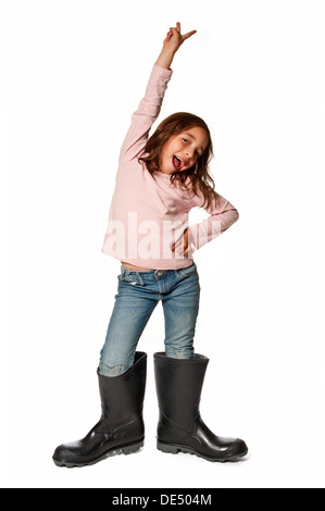 Sieben-jährige Mädchen tragen Gummistiefel, die viel zu groß sind Stockfoto