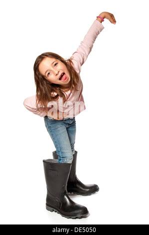 Sieben-jährige Mädchen tragen Gummistiefel, die viel zu groß sind Stockfoto