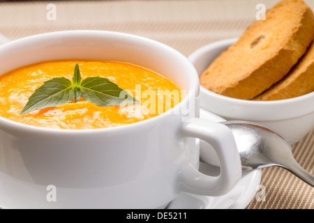 Kürbissuppe in weiße Schüssel mit frischem Basilikum Stockfoto