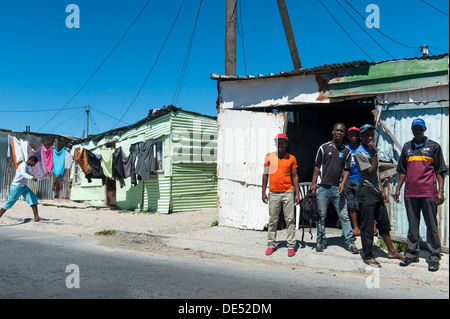 Menschen stehen vor einer Blechhütte in Khayelitsha, einem teilweise informellen Township in Kapstadt, Westkap, Südafrika Stockfoto