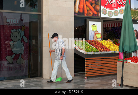 Ein Reinigung Arbeiter reinigt & fegen einen Marktplatz in Mazkeret Batya, Israel Stockfoto