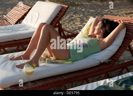 Frau, 45 Jahre, in einem Strand-Outfit, entspannen Sie sich auf einer Sonnenliege mit einem Piña Colada cocktail, Playa Samara, Nicoya Halbinsel Stockfoto