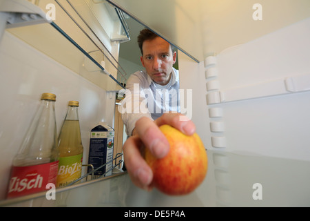 Berlin, Deutschland, Claus bringt einen Apfel aus seiner fast leerer Kühlschrank Stockfoto