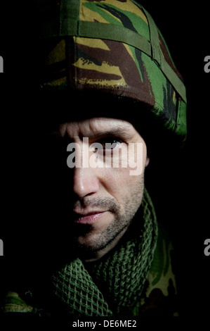 Porträt des britischen Soldaten Kampf Müdigkeit leiden, er ist unrasiert und Hälfte seines Gesichts ist im tiefen Schatten. Stockfoto