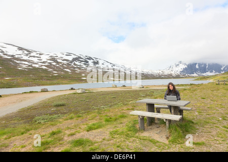 Junges Mädchen arbeiten auf einem Laptop zwischen den Bergen Stockfoto