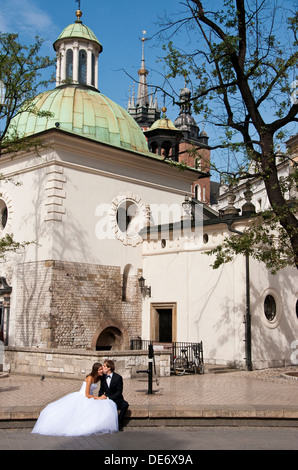 Krakauer Hauptmarkt mit Bräutigam küssen Braut vor der Kirche von Wojciech (aka St. Adalbert). Stockfoto