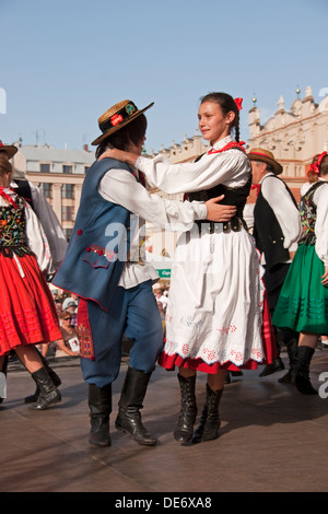 Volkstänzer in Krakauer Hauptmarkt tragen traditionelle bestickte Kleidung. Stockfoto