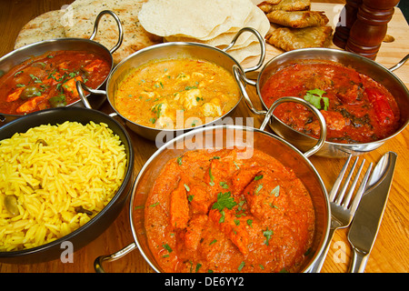 Vielfältige Auswahl an indischen Gerichten am Tisch Chicken Tikka, einschließlich Rindfleisch Rogan Josh, Jalfrezi Huhn und chicken Korma. Stockfoto