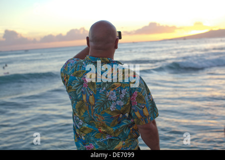 Tourist in Hawaii nimmt ein Bild des Ozeans Sonnenuntergang mit seinem Handy. Stockfoto