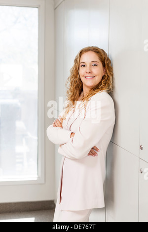 Zuversichtlich, Geschäftsfrau, stehend im Büro Flur mit verschränkten Armen Stockfoto