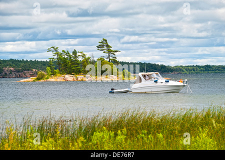 Motorboot mit Beiboot auf See in Georgian Bay, Ontario, Kanada verankert Stockfoto