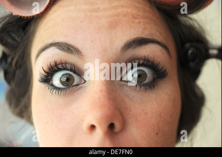 Junge schöne Frau der 20er Jahre mit Rollen in ihr Haar und tragen Wimpernverlängerung, immer bereit für eine Nacht Stockfoto