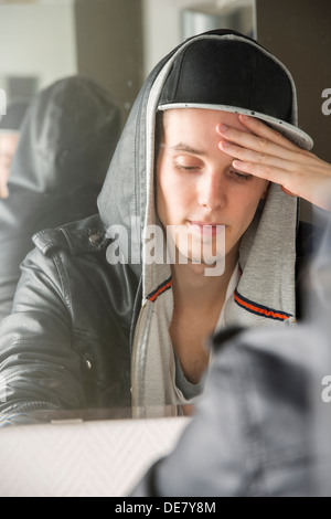 Besorgnis erregend und gestresste junger Mann mit coole Haltung sitzen vor Spiegel Stockfoto