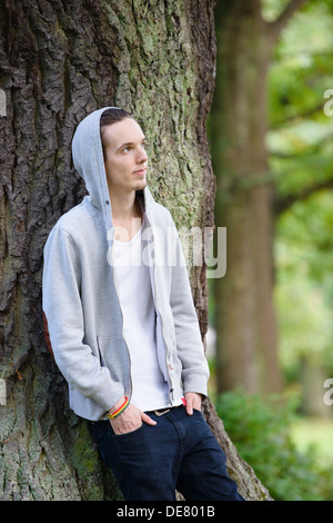 Junger Mann alleine stehen und denken in einem Wald Stockfoto