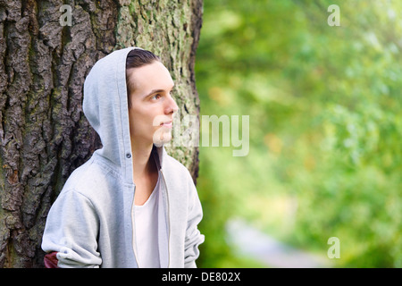 Junger Mann alleine stehen und denken in einem Wald Stockfoto