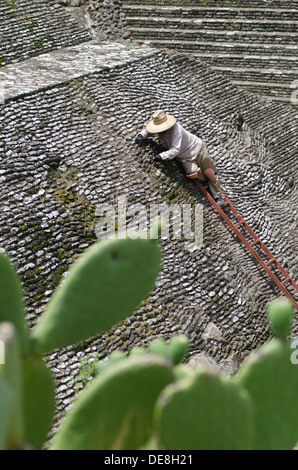 Ein Arbeiter auf einer Leiter, die Reinigung des Mauerwerkes Bestandteil der großen Pyramide von Cholula in Mexiko. Stockfoto