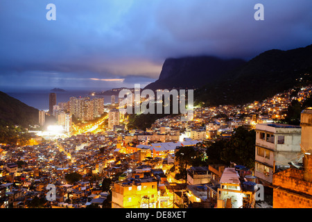 Nacht-Ansicht von oben der Favela da Rocinha, Oberschicht Sao Conrado Nachbarschaft im Hintergrund, Rio De Janeiro, Brasilien. Stockfoto
