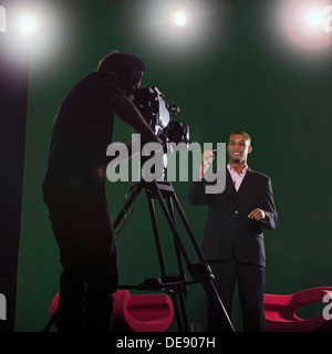 Moderator im Gespräch mit Kamera mit Silhouette der Kameramann im Vordergrund und Studio Lichter im Hintergrund. Stockfoto