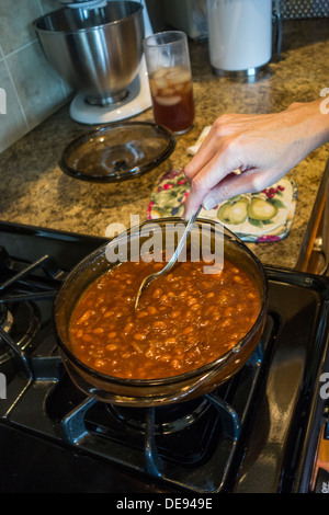 Hausgemachte, gebackene Bohnen, die für den Backofen bereit sind und vom Koch gerührt werden. USA Stockfoto