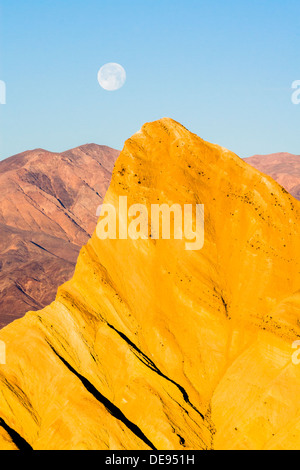 Manly Beacon Peak und Vollmond im Morgenlicht Kurz nach Sonnenaufgang. Zabriskie Point, Death Valley National Park, Kalifornien. Stockfoto
