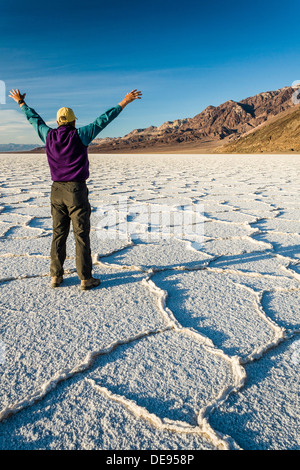 Ein Mann mit ausgebreiteten Armen steht in der geometrischen Muster von Badwater Salzsee. Death Valley National Park, Kalifornien, USA Stockfoto