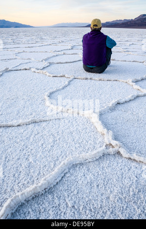 Ein Mann sitzt in geometrischen Mustern Salzpfanne in der Nähe von Badwater im Death Valley Nationalpark, Kalifornien. Stockfoto