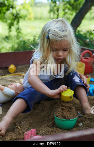 Kleines blondes Mädchen spielen im Sandkasten im Sommergarten Stockfoto