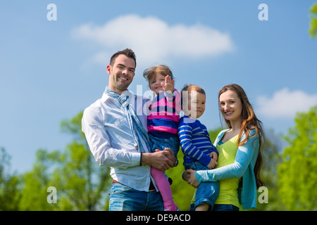 Glückliche Familie mit Tochter und Sohn gehen auf einer Wiese im Sommer Stockfoto