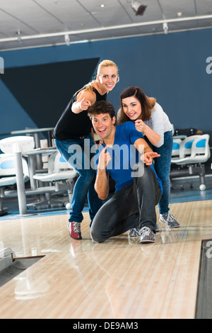 Gruppe von Freunden in einer Bowlingbahn, Spaß haben, die Mädchen jubeln dann er bekommen einen Streik Stockfoto