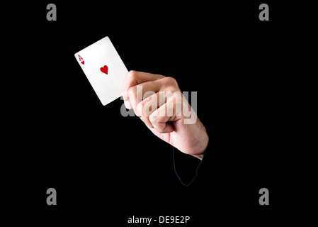 Hand, die Herz-Karte-Ass auf schwarzem Hintergrund Stockfoto