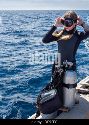 Kaukasische Frau auf einem Boot im Meer passt ihre Brille in der Vorbereitung für den Tauchsport. Stockfoto