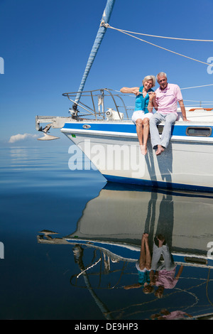 Ein glückliches senior paar sitzt auf der Vorderseite eines Segelbootes auf einem ruhigen blauen Meer Stockfoto