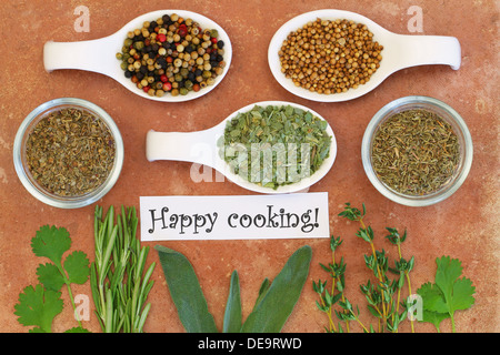 Happy cooking Karte mit Auswahl von Kräutern und Gewürzen auf Terrakotta Oberfläche Stockfoto